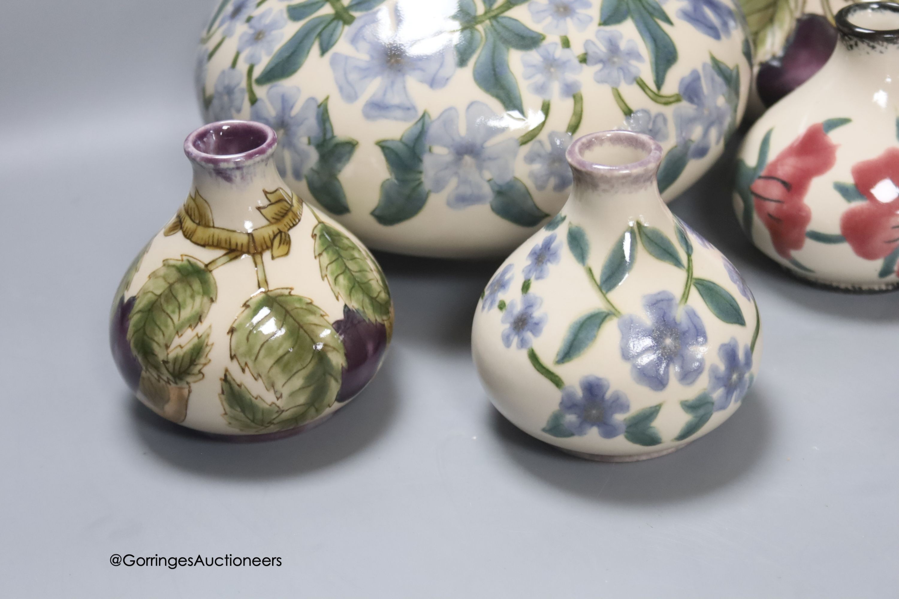 Three Cobridge floral vases and a jug and vase with plum design, tallest 21cm